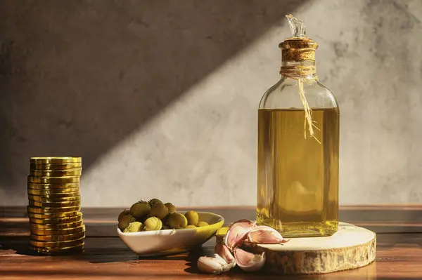 Zeytin ve sarımsaklı bir şişe zeytinyağı yanında da petrol fiyatlarına kıyasla altın sikkeler, enflasyon fiyat artışı.