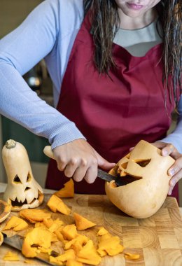 Cadılar Bayramı süsü hazırlayan yaratıcı kız, Cadılar Bayramı 'nı evde kutlayan aile ve balkabağı hazırlayan kız..