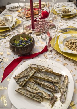 Noel 'i kutlamak için öndeki ızgara jilet tabağında yemek masası. Yay, kalp ve yanan mumlarla Noel süslemesi.