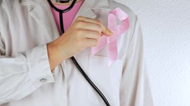 Steteskoplu kadın doktor pembe kurdele gösteriyor, kapat. Göğüs kanseri konsepti, yatay çekim.
