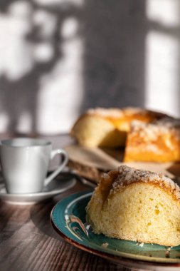 Rosco de Reyes arka planda, ön planda, yanında bir fincan kahveyle birlikte bir parça tatlı dilimlenmiş, tipik İspanyol tatlısı, Noel atıştırmalığı. Üç Krallar Günü.