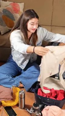 Elinde defter olan genç bir kız seyahat için bavulunu hazırlamak için listeyi kontrol eder. Seyahate, tatile, boş zamanlara hazırlan.