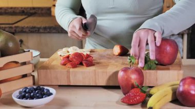 Kadın saglikli kase hazirliyor muzlu, çilekli ve yaban mersinli. Kır mutfaginda ahşap tahta üzerinde. El ve gövde detaylarıyla orta boy çekim, sağlıklı beslenme, doğal yemek ve dengeli yaşam tarzı..