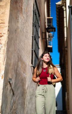 Eski tip sırt çantalı ve sakin görünümlü yarım boyda bir kız. Odak kentsel arkaplan ve metin için boş alan. Malaga 'nın merkezinde sokak manzarası.