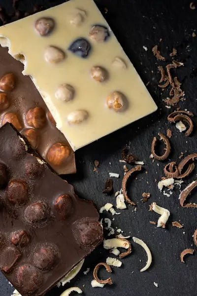 Çikolata istiflenmiş dikey yakın çekim. Çikolata parçacıkları siyah arka planda, kırsal ve iştah açıcı stilde görülür..