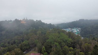 Bereketli yeşil bir tropikal ormanın üzerinde yuvarlanan sisli hava manzarası Chiang Mai 'deki uzak bir dağın tepesine tünemiş bir Budist tapınağını kısmen karartmıştı.