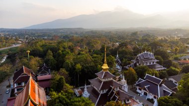 Wat Pa Dara Phirom Phra Aram Luang Tapınağı 'nın arka planında dağlarla birlikte Chiang Mai, Tayland yakınlarındaki Mae Rim bölgesindeki Budist tapınakları ve yemyeşil bitkilerin hava manzarası.
