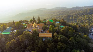 Wat Phra 'nın havadan görünüşü Doi Suthep Budist tapınağının Chiang Mai, Tayland' daki bir dağın tepesinde puslu bir gündoğumunda parladığı yönünde.