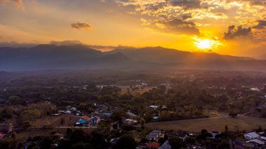 Altın saat güneş ışığı, ağaçların ve tarlaların arasında yuva yapmış pitoresk bir vadi ve evler, Tayland 'ın Chiang Mai yakınlarındaki Mae Rim' de huzurlu ve huzurlu bir manzara yaratıyor..