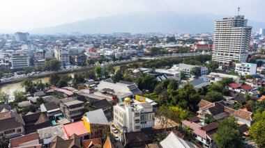Tayland 'ın Chiang Mai kentinin havadan görünüşü Ping Nehri' ni gösteriyor. Geleneksel evler, modern binalar ve kirli sis havası ile yemyeşil alanlar arasında gidip geliyor.