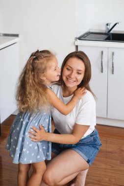 Çocuk mutfakta annesinin kulağına bir şeyler fısıldıyor. Çocuk bir sır söylüyor. Küçük kız annenle mutlu bir şekilde konuşuyor ve izin istiyor.