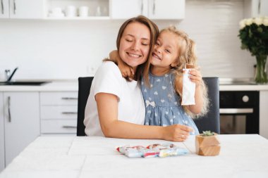 Çocuk mutfakta tatlı atıştırmalıklar yiyor. Mutlu çocuk, annesiyle evde lezzetli şekerlemeler yiyor. Beyaz, sarışın aile.