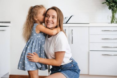 Çocuk mutfakta annesinin kulağına bir şeyler fısıldıyor. Çocuk bir sır söylüyor. Küçük kız annenle mutlu bir şekilde konuşuyor ve izin istiyor.