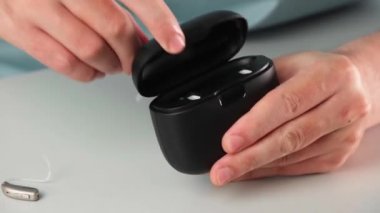 Hastanın işitme cihazını dahili güç bankası olan özel taşınabilir Smart Charger ile şarj etmesi. Erkeklerin elindeki dava işitme cihazlarını kuru ve güvenli tutuyor.