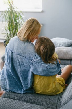 Genç, sevgi dolu bir anne genç kızına sarılıyor, anne çocuğa koşulsuz sevgi gösteriyor, anne evde birlikte vakit geçirirken genç kıza sarılıyor. Arkadan bak.