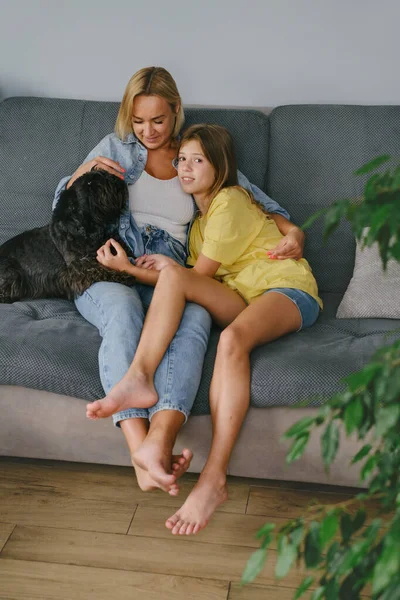 stock image Young loving mother hugging her teenage daughter, mom demonstrating unconditional love for child, mommy cuddling supporting teen girl while spending time together at home with dogMother-daughter bond