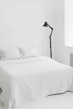 Minimalist, tamamen beyaz yatak odası. İskandinav tarzında bembeyaz bir daire. Uzayı kopyala Minimum tasarım. İç mekan, konfor ve yatak konsepti - evde yatak