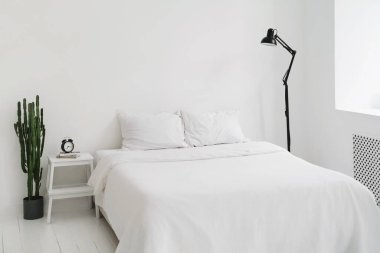 Minimalist, tamamen beyaz yatak odası. İskandinav tarzında bembeyaz bir daire. Uzayı kopyala Minimum tasarım. İç mekan, konfor ve yatak konsepti - evde yatak