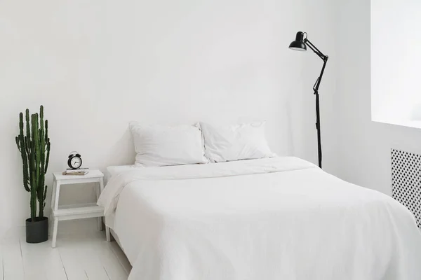 Minimalist, tamamen beyaz yatak odası. İskandinav tarzında bembeyaz bir daire. Uzayı kopyala Minimum tasarım. İç mekan, konfor ve yatak konsepti - evde yatak