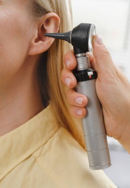Kadın hasta doktor otolaringolojistte işitme kontrolü yapıyor. Kadın için işitme sınavı. Otolaryngologist doktor, tıbbi klinikte otoskop ya da auriskop kullanarak olgun kadınların kulaklarını kontrol ediyor.