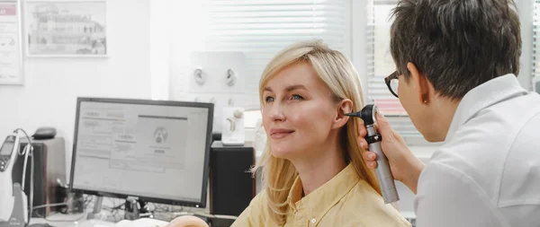 Kadın hasta doktor otolaringolojistte işitme kontrolü yapıyor. Kadın için işitme sınavı. Otolaryngologist doktor, tıbbi klinikte otoskop ya da auriskop kullanarak olgun kadınların kulaklarını kontrol ediyor.