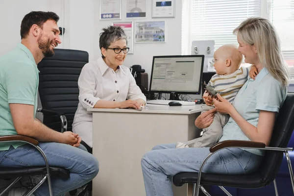 チェックアップを聞いている子供たちの家族 幼児相談医聴覚士の両親 病院の医務室で赤ちゃんを持つお母さん — ストック写真