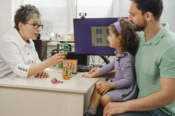 speech therapist working with child who has hearing problems. Rehabilitation teacher of the deaf consulting father with daughter. Speech therapist working with child who has hearing problems