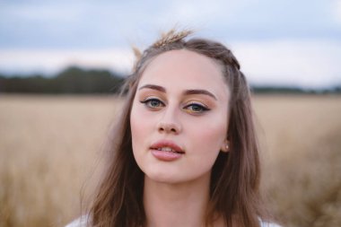 Buğday tarlasında güzel bir kadın. Açık havada makyajlı genç bir bayan. Çavdarlı Ukrayna tarım arazisi. Boho şık tarzı.