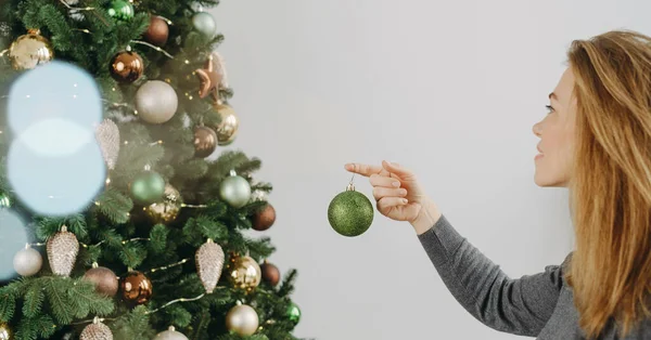 大きなクリスマスツリーを飾る女性 中年女性が手元に緑のバブルを抱え 木の枝に吊るしています スペースをコピーする グリーティングカード バナー — ストック写真