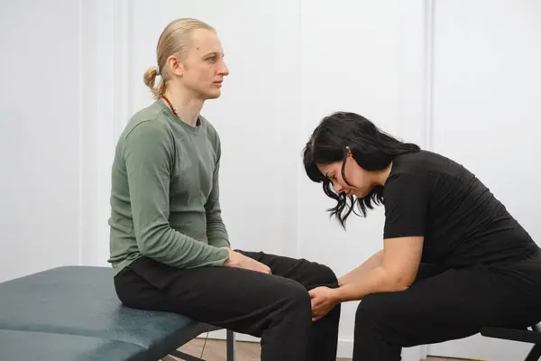 Knee therapy. Patient at the physiotherapy doing physical exercises with his therapist. rehabilitation center. Alternative treatment osteopath. Feldenkrais method