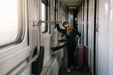 Küçük çocuk gün batımında büyük bir bavulla trene biniyor, parlak güneş ışığı, çocuklarla birlikte tren yolu ile atmosferik yolculuk. Akşamları yolu keşfetmekten mutlu bir kız. Heyecanlı bir aile gezisi.