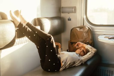 Gün batımında trene binmekten yorgun bir çocuk, parlak güneş ışığı, çocuklarla birlikte demiryolu ile atmosferik yolculuk. Yolcu kayan vagonun kanepesinde dinleniyor. Uzun bir aile gezisi