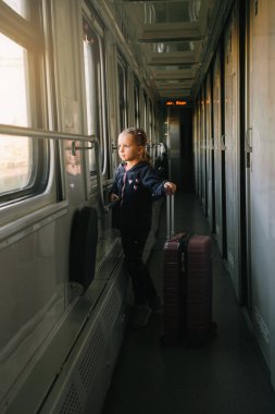 Gün batımında tren penceresinden bakan küçük bir çocuk, parlak güneş ışığı, çocuklarla birlikte demiryolu ile atmosferik seyahat. Akşamları yolu keşfetmekten mutlu bir kız. Heyecanlı bir aile gezisi.