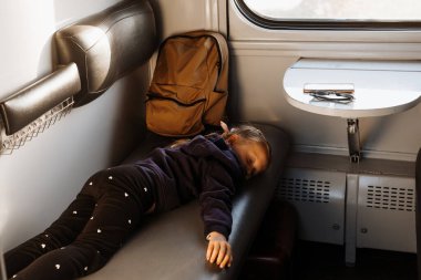 Gün batımında trene binmekten yorgun bir çocuk, parlak güneş ışığı, çocuklarla birlikte demiryolu ile atmosferik yolculuk. Yolcu kayan vagonun kanepesinde dinleniyor. Uzun bir aile gezisi