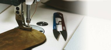 Eko deri ürünleri dikiyorum. Dikiş makinesinin ve eko deri parçasının yakın çekimi. Dikiş makinesi, terzilik, küçük işletme konsepti. Zanaatkar atölyesi. Boşluğu kopyala