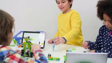 Çocuklar okulda kodlama, fen ve teknoloji öğreniyor. Afrika kökenli Amerikalı ve Kafkasyalı çocuklar STEM dersinde dizüstü bilgisayarlarıyla geziyorlar. Modern yenilikçi eğitimde çeşitlilik