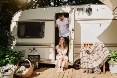 Kamp ve seyahat. Mutlu çift dışarıda karavanın yanında dinleniyor. Adam ve kadın yolculuklarında. 