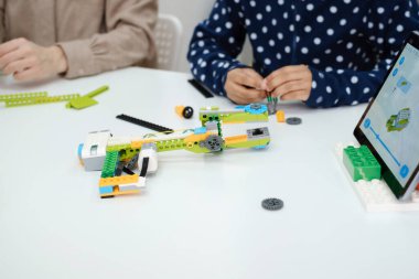 Kodlama sınıfı, liseli kız robot kol mekanizması yapıyor. Bilim yapan çok ırklı çocuklar, tabletli teknolojik görevler. Modern eğitim Afrikalı Amerikalı kız ders üzerinde deney yapıyor.