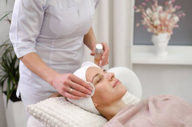 Kozmetik uzmanı modern estetik kliniğinde pamuk yastıkla cilt temizleme, bakım ve tedavi prosedürleri yapıyor. Kadın güzellik salonunda yüzüne tonik sürüyor.