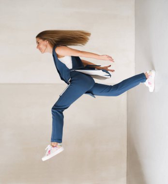 Yaratıcı denge, genç bir kadının düşmeye ya da adım atmaya hazır olması. İş kostümü içinde mutlu. Aydınlık odada kararlı, güçlü bir kadının cesur moda portresi. Modern doğaüstü trend