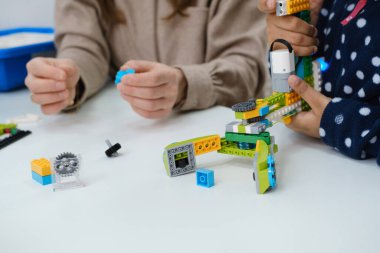 STEM dersindeki çoklu etnik çocuklar, kadın öğretmenle sınıfta robot inşa ediyorlar. Çocuklar, modern bilim okulunda Afrika kökenli Amerikalı, Kafkas öğrencilerin öğrenme teknolojisinde elektronik kol modeli yapıyorlar.