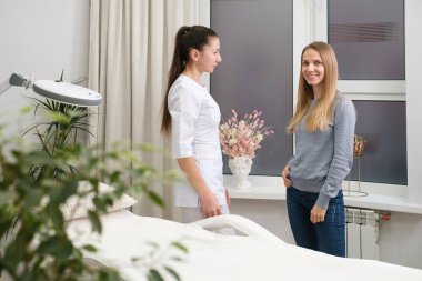 Müşteri, dermatoloji kozmetik uzmanıyla görüşüyor. Cilt sorunları ve terapi yöntemleri hakkında konuşuyor. Tedavi için bölgeleri gösteren bir kadın. Prosedürden önce müşteri ile güzellik uzmanı