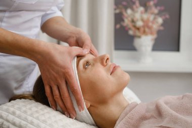 Müşteri kadın dermatoloji kozmetik uzmanıyla masaj yaptırıyor klinikte, cilt sorunlarıyla ilgili. Tedavi için bölgeleri gösteren bir kadın. Kuaförde prosedürden önce müşteriyle güzellik uzmanı