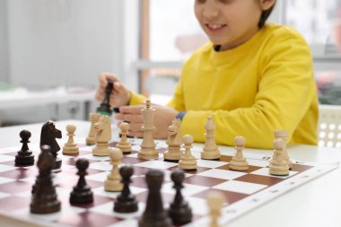 Yakın çekimde, satranç oynayan beyaz çocuk. Sınıfta ya da okul dersinde satrancın arkasında mutlu konsantre çocuk. Heyecanlı zeki ilkokul çocuğu yakın plan masa oyunu oynuyor.