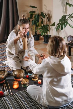 Şarkı kaseleri, titreşim masajı ve alternatif terapi ile ses iyileştirme. Yeşil atmosferik stüdyoda akıl sağlığı hizmetleri. Kadın perküsyon enstrümanı çalıyor. Şarkı söyleyerek, meditasyon yaparak.