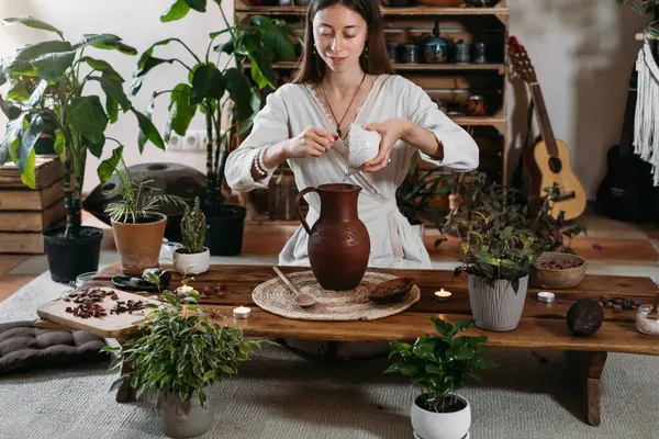 Kakaoyla sürahiye su dök. Bitkilerle dolu atmosferik boho tarzı kafede seremoni kakaosu hazırlıyorum. Kadınlar ayin için organik kakao fasulyelerinden sağlıklı içecekler pişiriyorlar. 