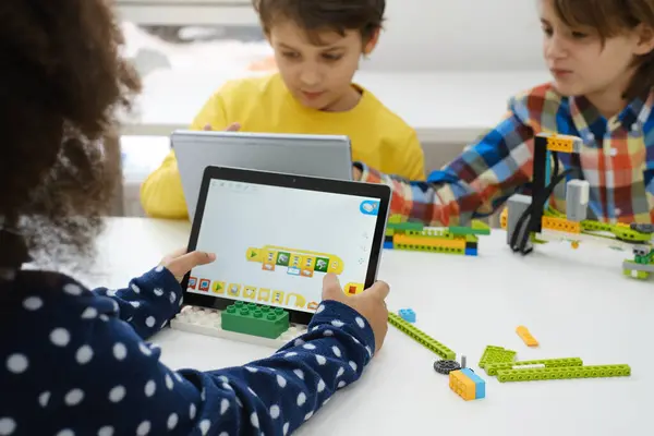 Bilgisayar Kodlama Sınıfı Öğrencileri Robot Araç Programı Yapıyor ve Öğreniyor. Okulda bilim, teknoloji ve kodlama görevlerini tabletle yapan çok ırklı çocuklar. Modern eğitim