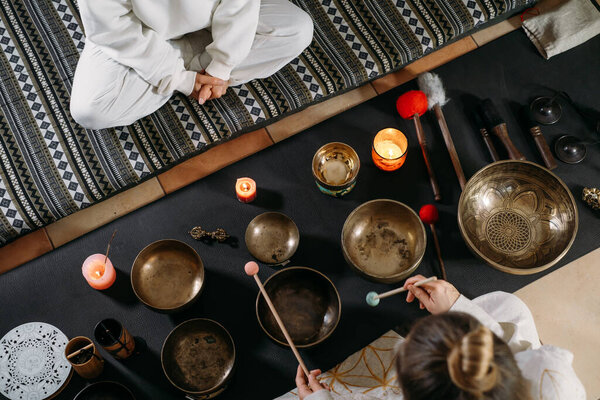 Поющие чаши вид сверху, звуковая альтернативная терапия исцеления. Женщина играет на ударных металлических музыкальных инструментах. Психическое здоровье с посредничеством, расслабляющим йога-массажем