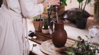 Atmosferik uzayda yeşil bitkiler ve mumlarla kakao seremonisi. Sıcak çikolatayı karıştıran Kakao fasulyesinden sağlıklı içecek yapan kadın.