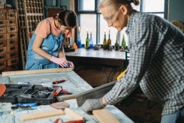 Erkek ve kadın atölyede çalışıyor, mobilya yapıyor, eski malzemeleri yeni ürünler için kullanıyor. Tüketimdeki farkındalık. Küçük bir aile şirketi. Ev için geri dönüşüm, sürdürülebilirlik yenileme bakımı